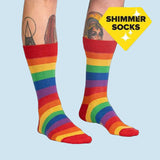 Rainbow striped socks worn by a person with tattoos on a white background, labeled 'Shimmer Socks'.