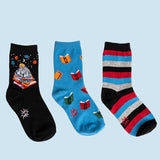 Three pairs of youth crew socks with various designs, including socks with books and stars, and striped socks.